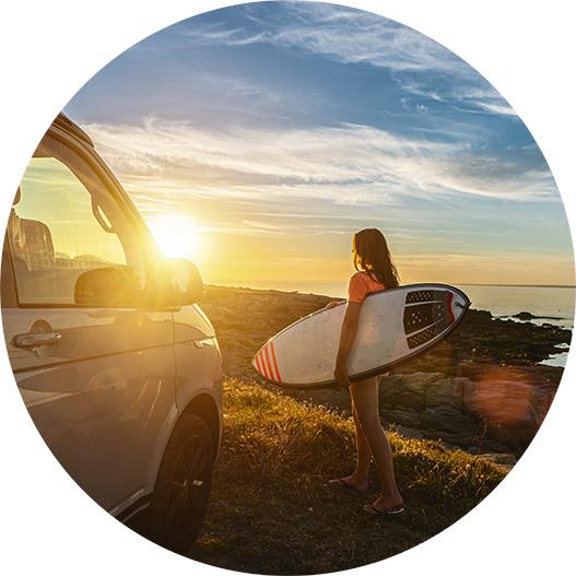Surfer holding a surfboard after exiting a transfer van